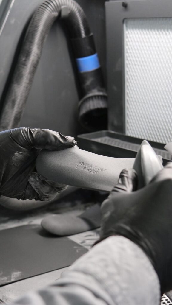 Gloved hands finishing an orthotic at the grinder