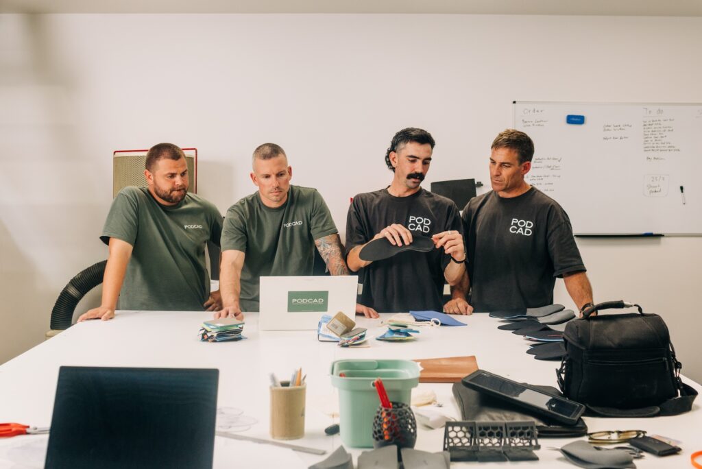 The PODCAD clinical and design team reviewing orthotics around a workshop table